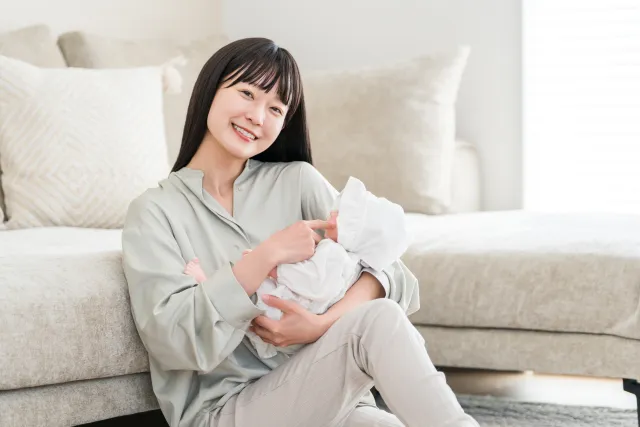 赤ちゃんを抱っこする母親。産後は抱っこや授乳で腰や骨盤まわりに負担がかかりやすい